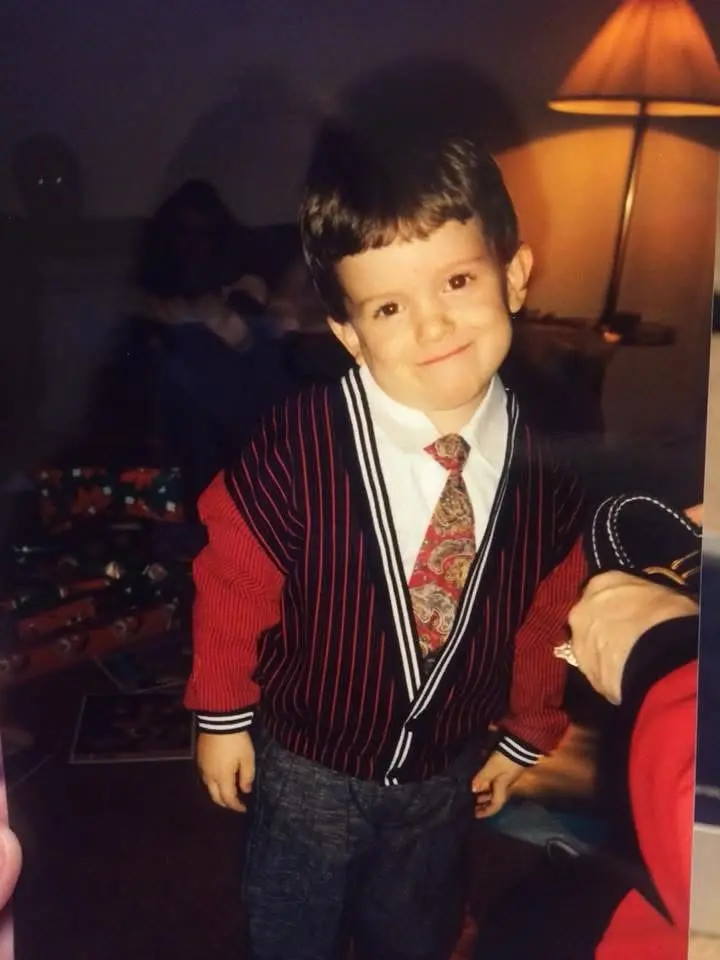 A young boy in a cardigan and tie